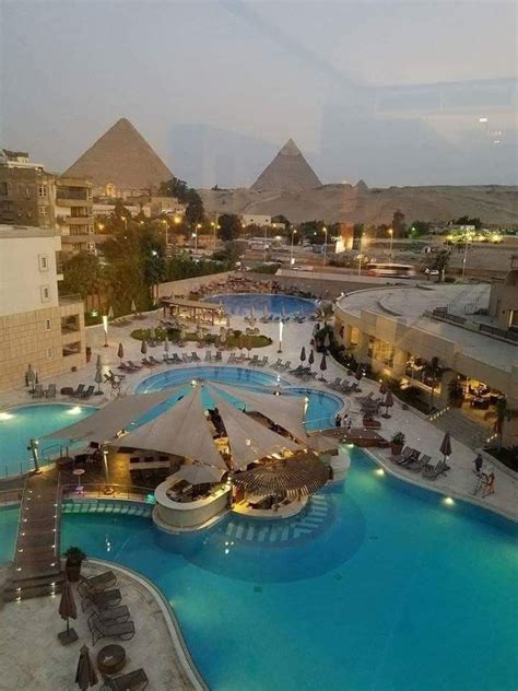 An Aerial View Of A Resort Pool At Night With The Pyramids In The