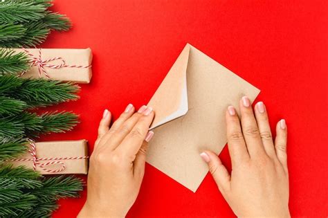 Manos de mujer envían carta con saludos navideños en marco de ramas de