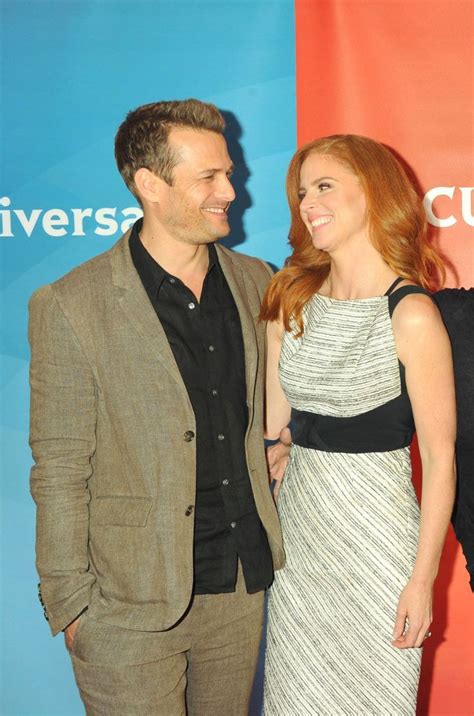 A Man And Woman Standing Next To Each Other On A Red Carpet At An Event