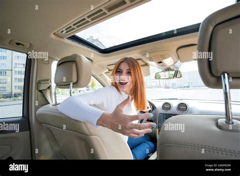 Wide Angle View Of Young Redhead Woman Driver Driving A Car Backwards