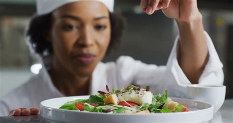 African American Female Chef Garnishing Dish And Similing In Restaurant