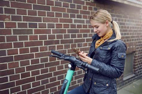 Une Jeune Femme Blonde Branchée En Veste De Cuir Debout à Son E scooter