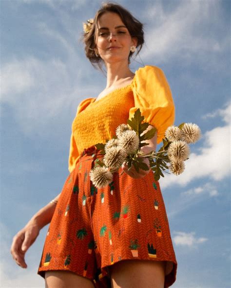 A Woman In An Orange Dress Holding Flowers