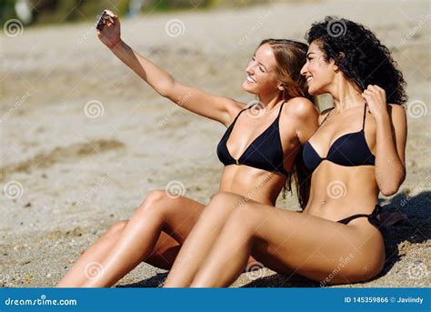 Two Women Taking Selfie Photograph With Smartphone In The Beach Stock