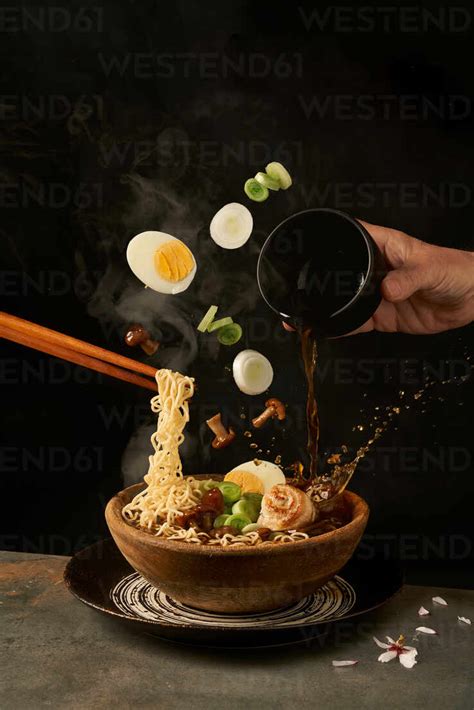 Cook Holding Noodles With Chopsticks And Adding Miso Broth Into Ramen