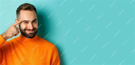 Free Photo Image Of Young Man In Orange Sweater Smiling And Pointing