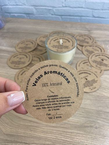 A Person Holding Up A Small Round Sticker Next To Some Candles On A Table