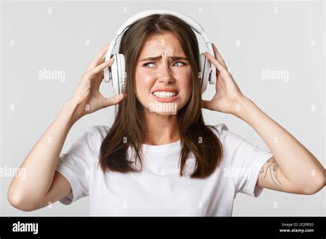 Close Up Of Annoyed Beautiful Girl In Wireless Headphones Complaining