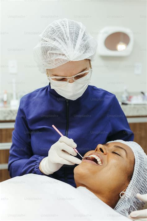 A Woman Getting Her Teeth Checked By A Dentist Photo Dentist Image On Unsplash