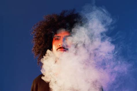 Premium Photo | Portrait of a stylish man with curly hair in smoke on a ...