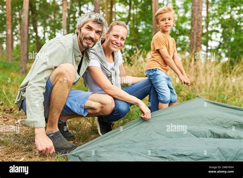 Portrait Of Happy Parents And Son Setting Up Tent Together While