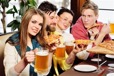 Grupo De Amigos Comiendo Pizza Y Bebiendo Cerveza En El Bar O En La