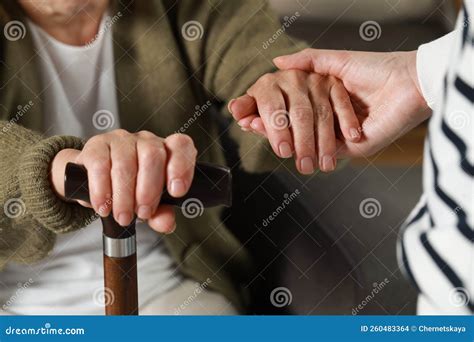 Caregiver And Elderly Woman With Walking Cane At Home Closeup Stock