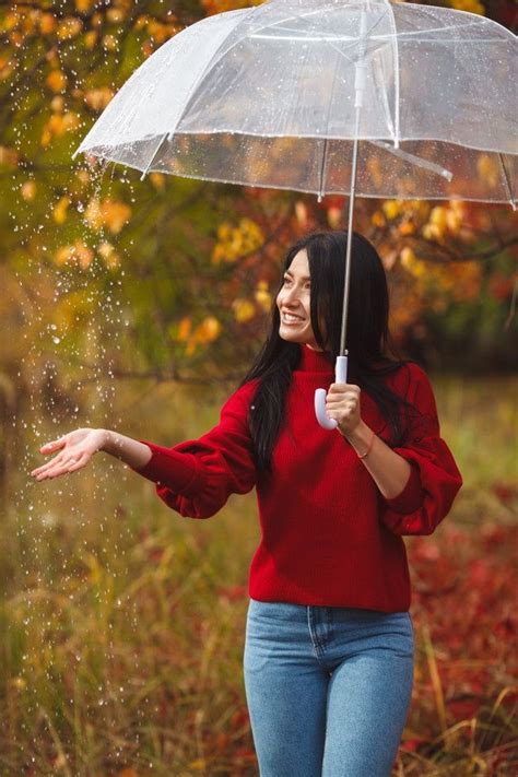 A Woman Holding An Umbrella In The Rain With Her Hands Outstretched Out