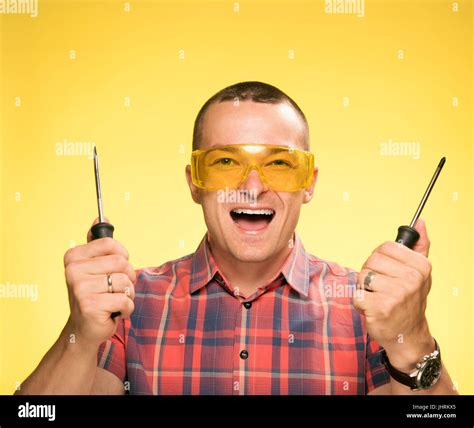 A Man With A Screwdriver On A Yellow Background Stock Photo Alamy