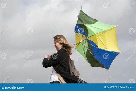 Woman Struggling To Hold Her Umbrella On A Windy Day Stock Photo