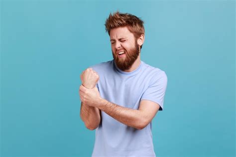 Homem De Camiseta Azul Massageando O Pulso Sentindo Dor Entorse