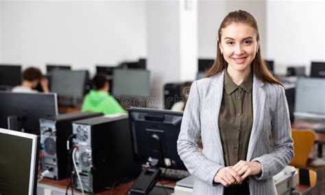 Portrait Of Positive Woman Teacher Standing In Computer Class Stock