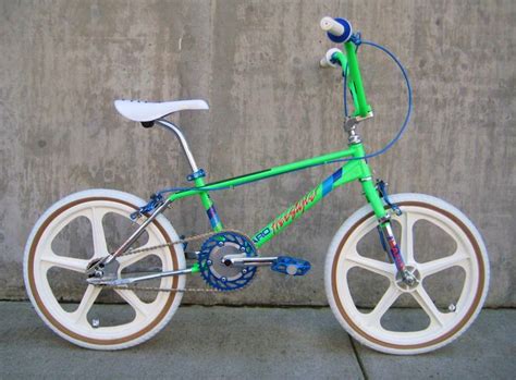 A Green And White Bike Parked Next To A Cement Wall With Wheels On The Rims