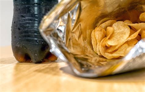 Opened Bag Of Potato Chips With A Bottle Of Soft Drink In The