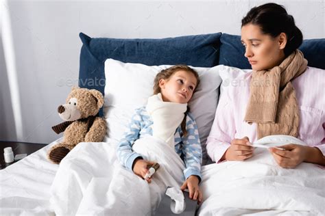 Diseased Mother And Daughter Looking At Each Other While Holding Nasal