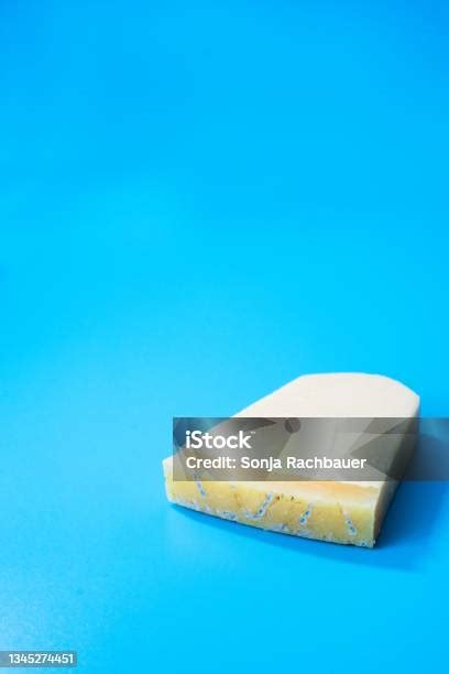 A Piece Of Moldy Parmesan Cheese On A Blue Background Stock Photo