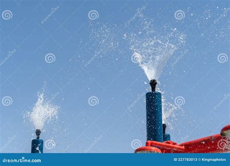 Two Blue Spray Water Park Sprinklers Spraying Water Into The Sky For