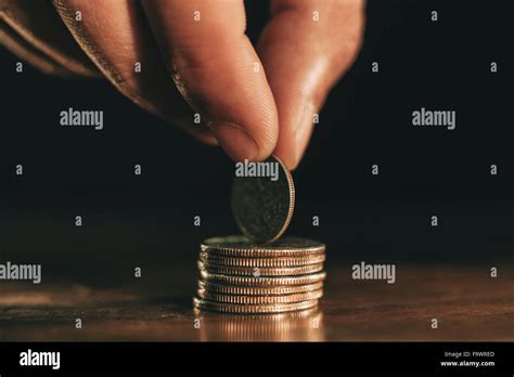 Hand Holding Coin On Top Of Stack Of Coins Stock Photo Alamy