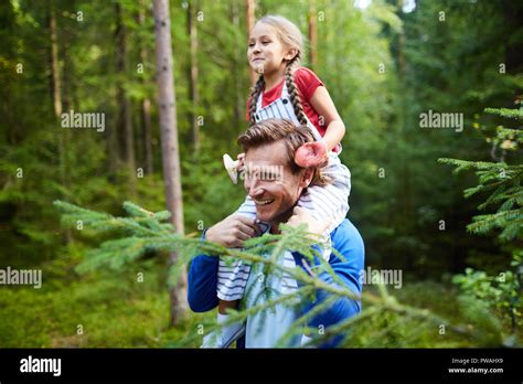 Happy Little Girl With Two Mushrooms Sitting On Her Dad Neck During