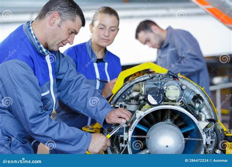 Aero Engineer And Apprentice Working On Helicopter In Hangar Stock