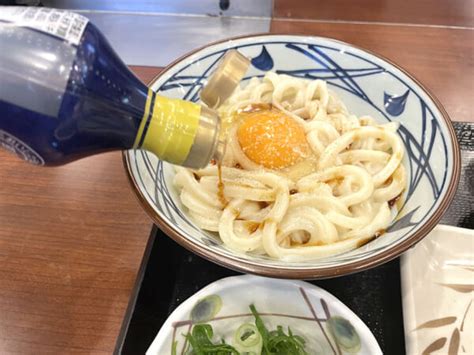 丸亀製麺の釜玉うどんと、だし醤油をかけていく おたくま経済新聞