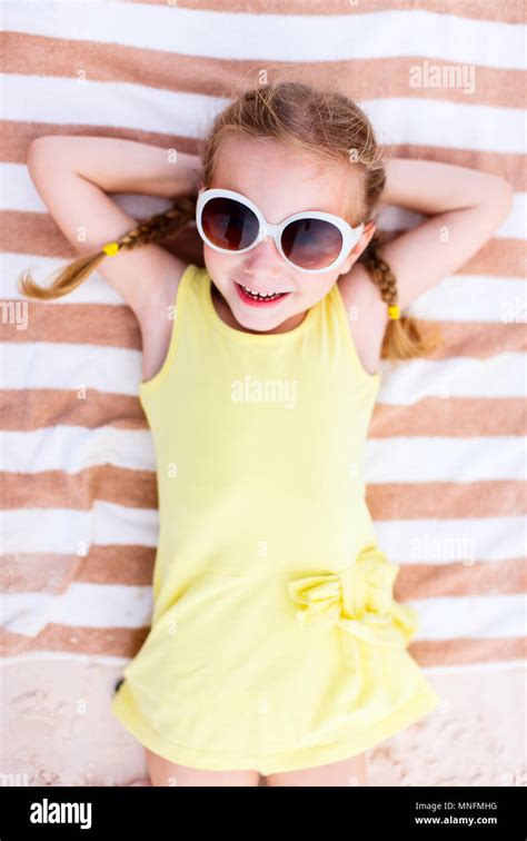 Adorable Little Girl Lying On A Beach Towel During Summer Vacation