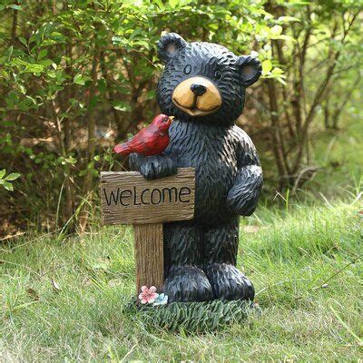 a statue of a bear holding a bird and welcome sign