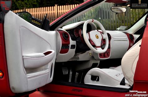 the interior of a red sports car with white leather trims and steering wheel controls