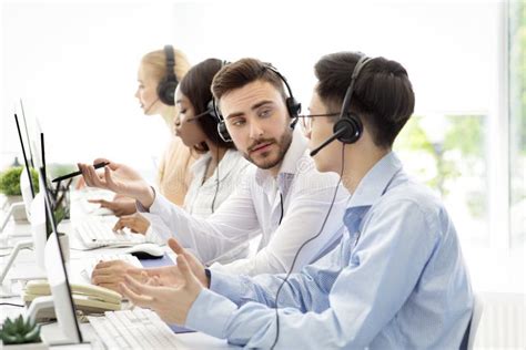 Operadores Masculinos Que Utilizan Auriculares Mientras Trabajan Foto