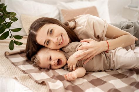 Une Jeune Belle Mère Avec Un Petit Garçon étreignant Sur Le Lit à La