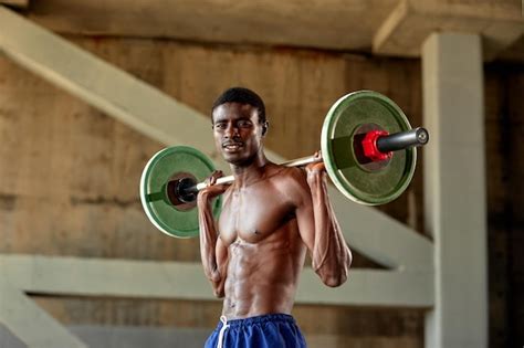 Premium Photo | Athletic black young man lifting a heavyweight barbell ...