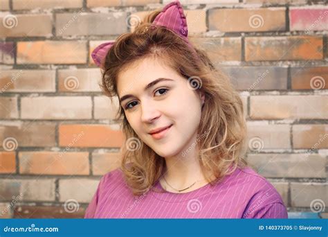 Portrait Of Young Woman In Cat Ears On Brick Wall Background Stock