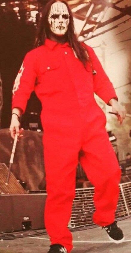 A Man In A Red Jumpsuit With A White Mask On His Face And Black Shoes