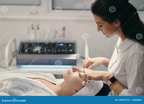 Female Cosmetologist Making Facial Treatment To A Beautiful Woma Stock