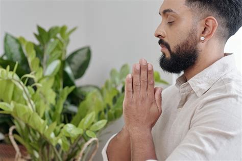 Bonito homem barbudo rezando as mãos em gesto de namaste fechando