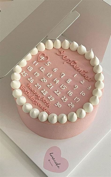 A Pink Birthday Cake With White Frosting And Hearts On The Top Is In A Box