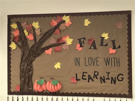 a bulletin board with autumn leaves and fall in love with learning written on the front