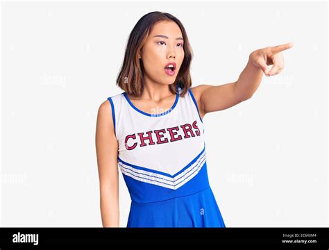 Young Beautiful Chinese Girl Wearing Cheerleader Uniform Pointing With