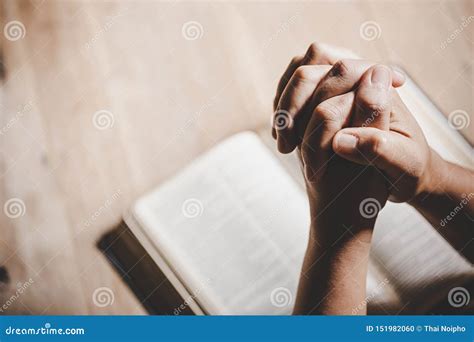 Hands Folded In Prayer On A Holy Bible In Church Concept For Faith