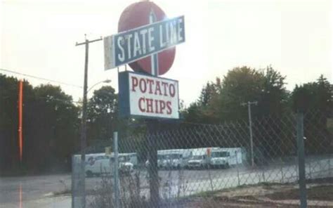 the sign for state line potato chips is posted behind a chain link fence