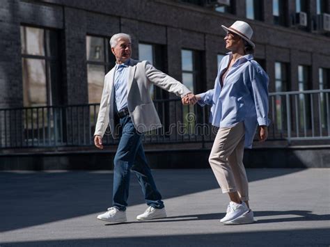 Stylish Mature Couple Gray Haired Man And Woman Holding Hands While Walking Around The City
