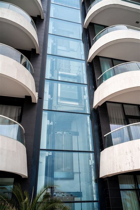 Glass Elevator in a Modern House, Hotel. the Elevator Rises between Two Rows of White Balconies ...