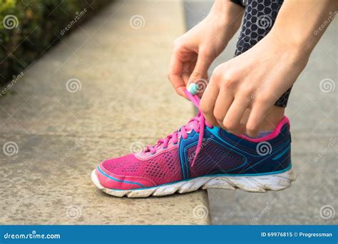 Las Manos Femeninas Con La Manicura Atan Cordones En Las Zapatillas De