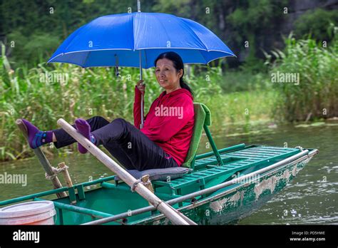 Asian Lady With A Blue Umbrealla Rowing A Boat With Her Feet Editorial